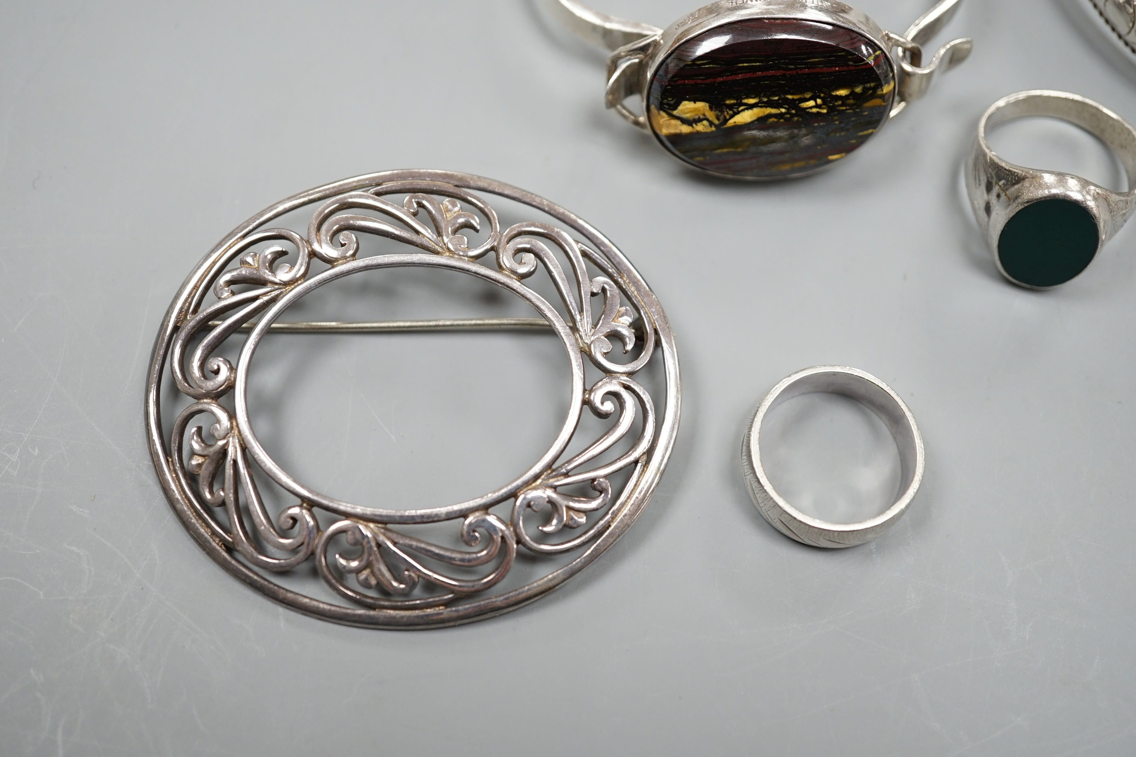 A 1970's silver and oval quartz set bangle, two other white metal bangles and three assorted rings.